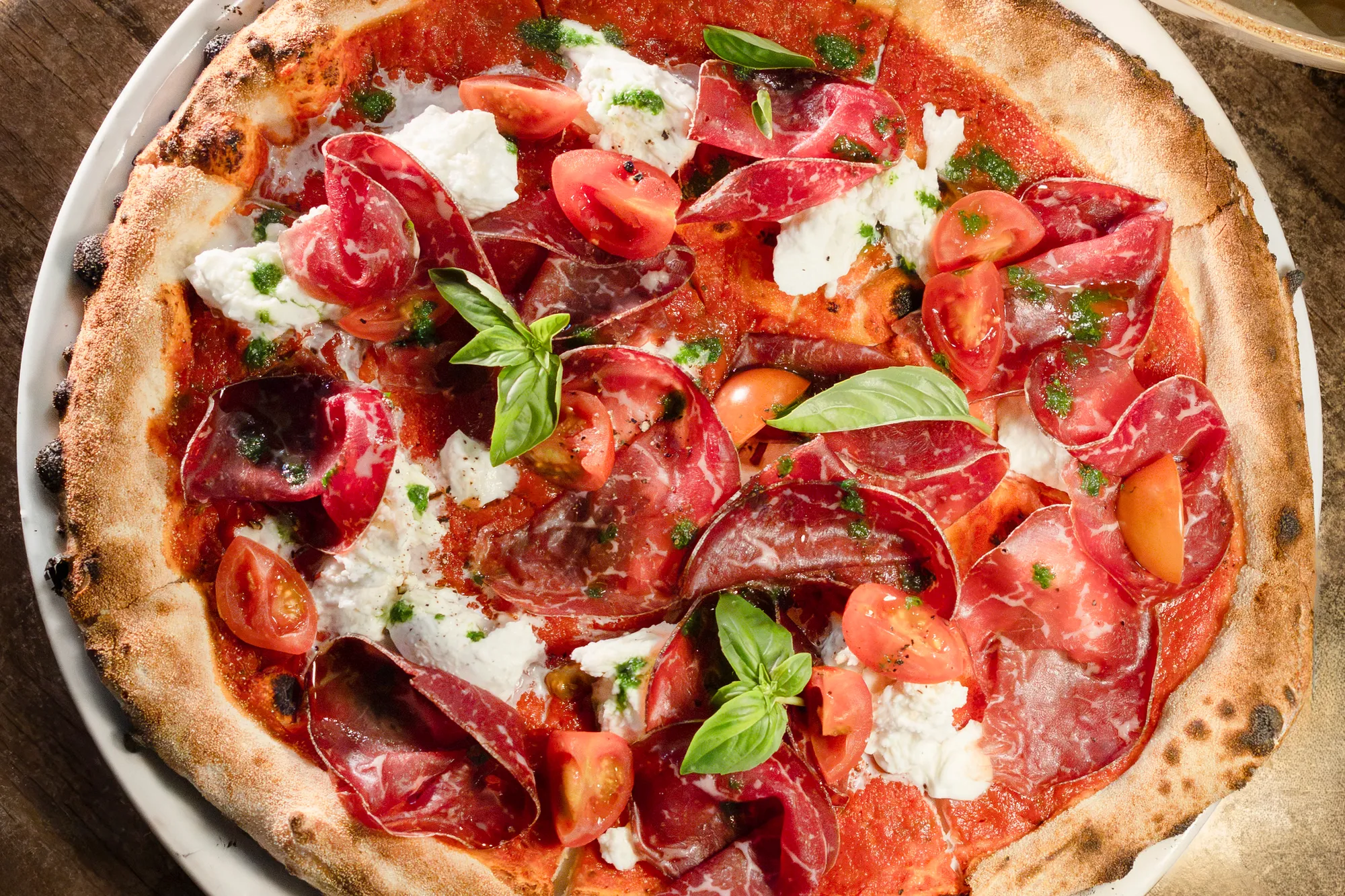 Wood-fired pizza with cured beef, tomatoes and basil